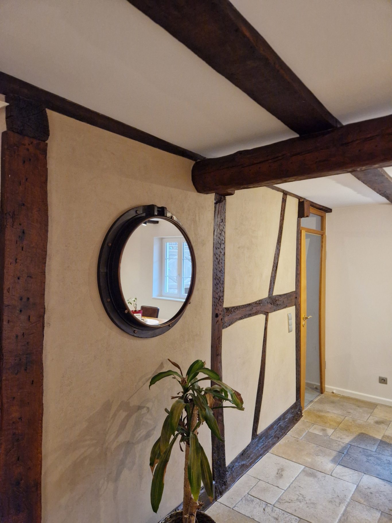Après - couloir Mur intérieur avec poutres en bois, miroir rond et plante en pot.