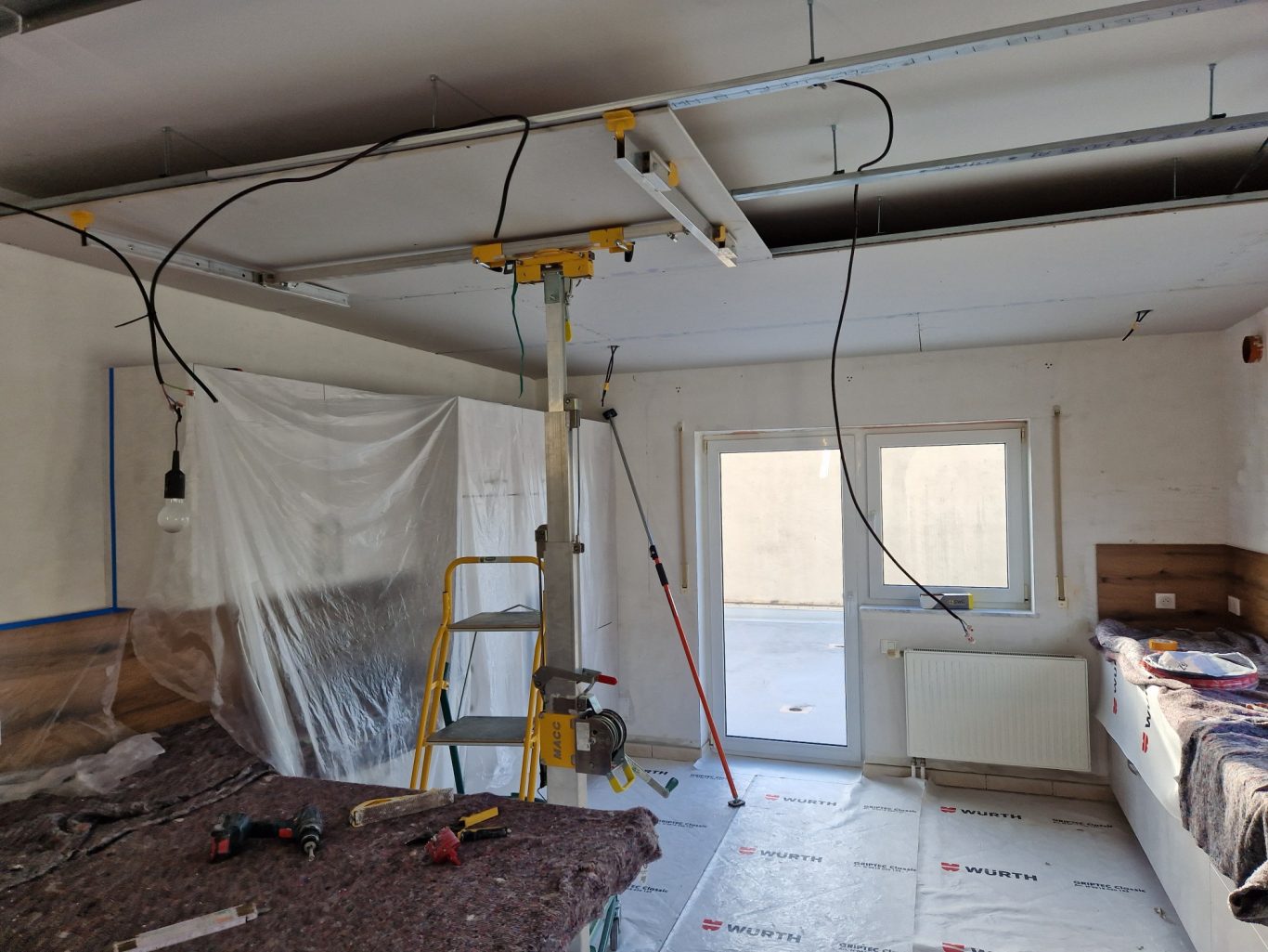 Avant - cuisine Intérieur en rénovation avec échelle, câbles suspendus et murs partiellement peints.