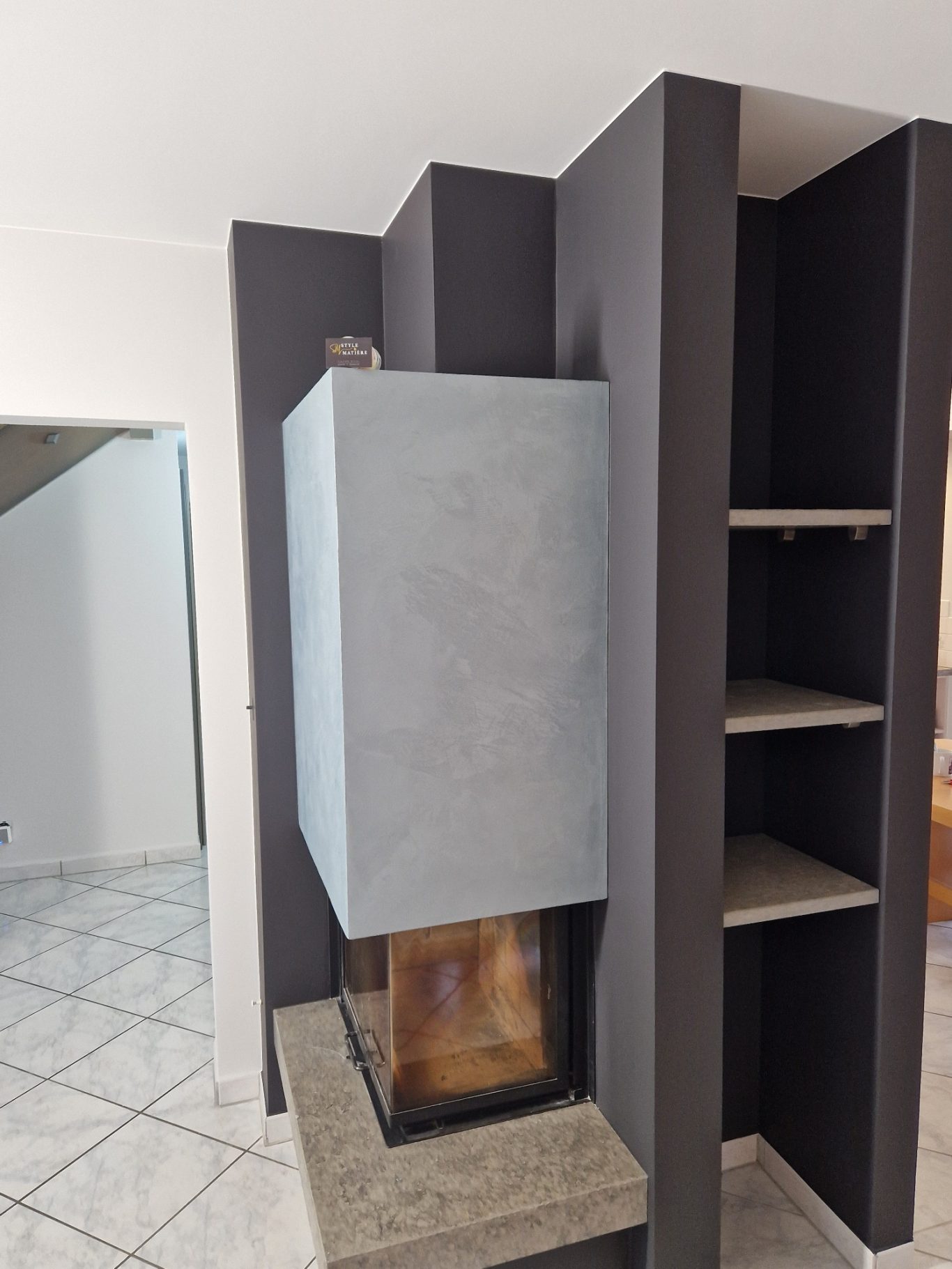 Après - Cheminée Cheminée moderne avec mur en béton et étagères intégrées.
